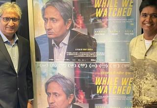 Journalist Ravish Kumar (left) and filmmaker Vinay Shukla (right) stand next to a poster of the film (Image credit: Instagram/@Whilewewatched)