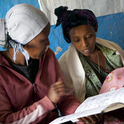 Two women bond over reading a book in Ethiopia. 