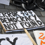 A protest sign laying on the ground reads "Error 404: Democracy Not Found." 