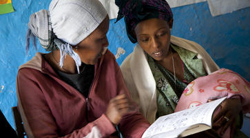 Two women bond over reading a book in Ethiopia. 