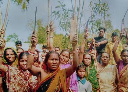 Several Indian women hold up branches. 